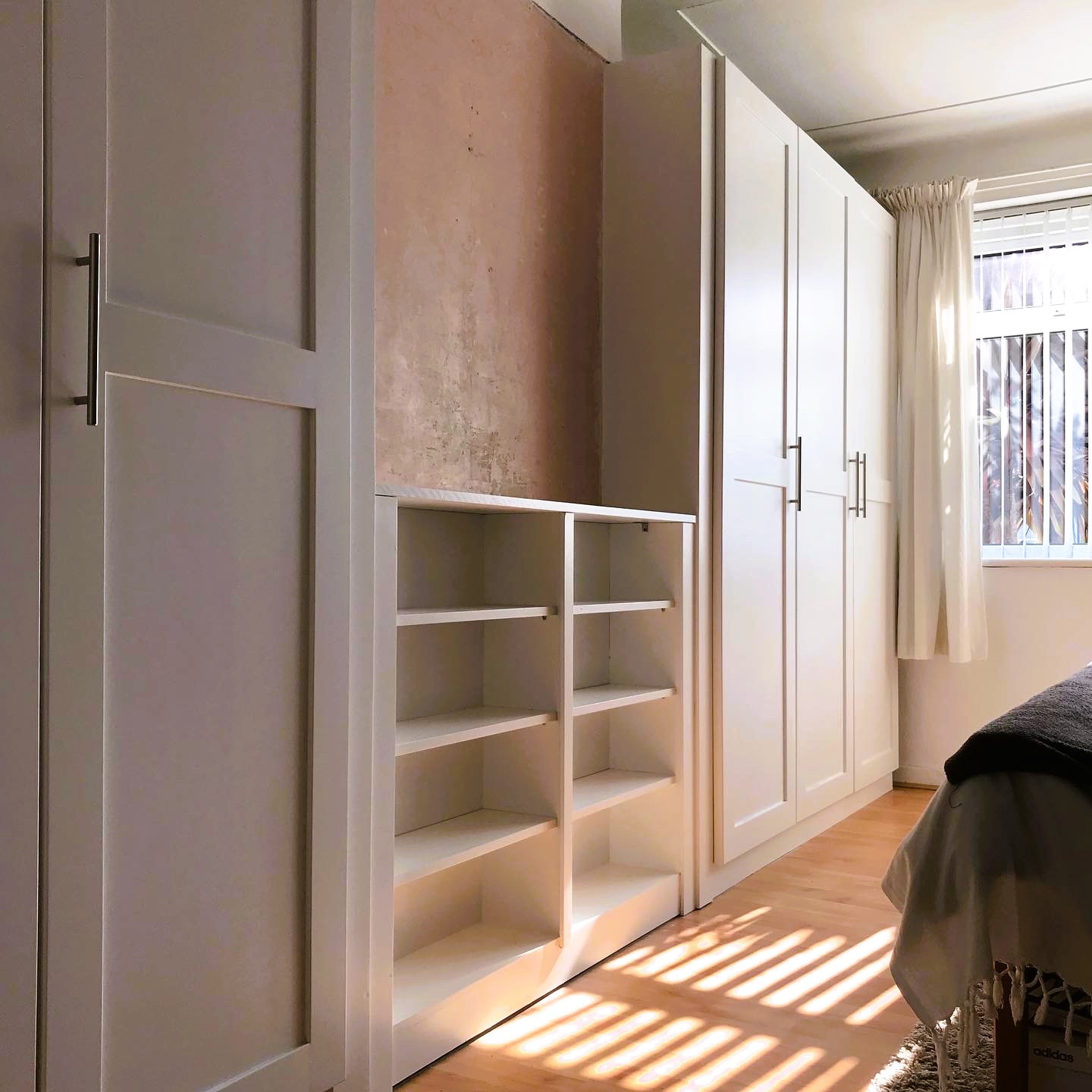 Fitted wardrobes with joining fitted open shelving in sunlight