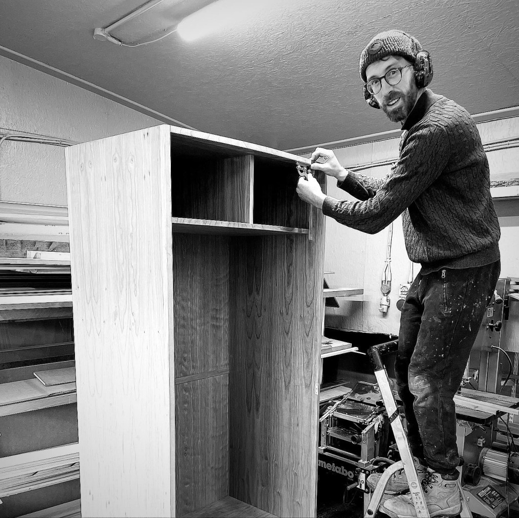 cabinet maker constructs a wooden wardrobe in a workshop